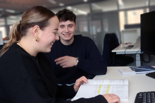 Auszubildende Industriekaufleute lächelnd am Schreibtisch