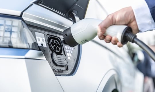 The driver of the electric car inserts the electrical connector to charge the batteries.