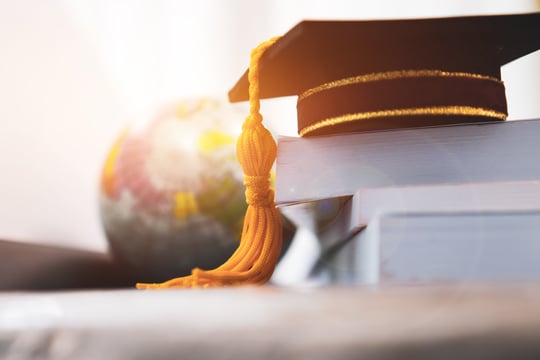 Universitaetsabschluss Hut auf Büchern im Fokus